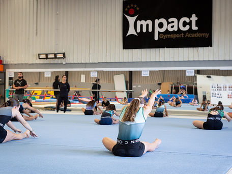 Classes Gymnastics class stretching in front of coaches and full length mirror